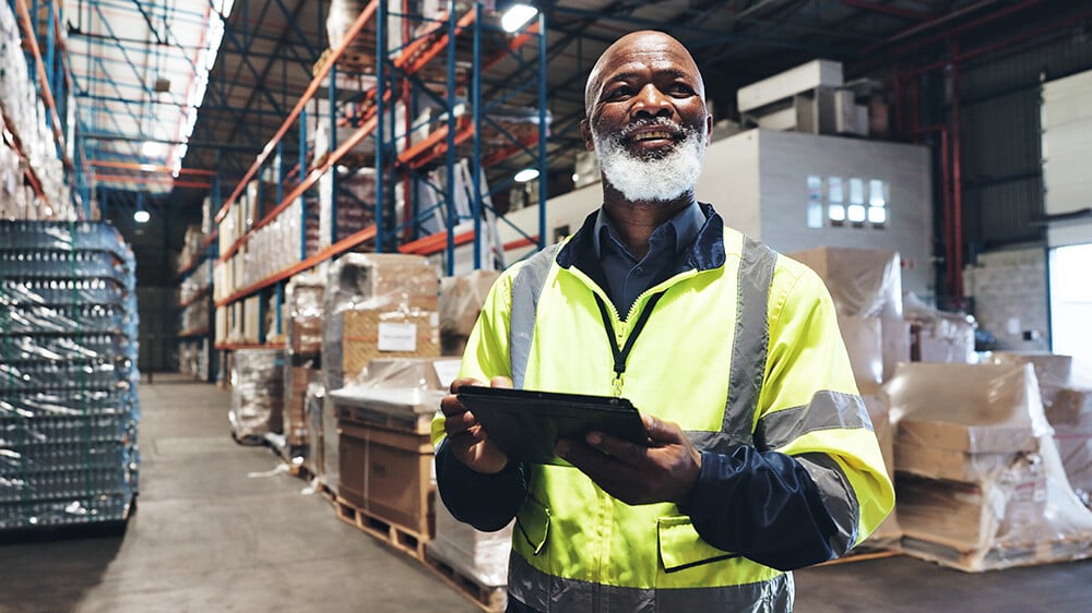 smiling warehouse employee standing in front of products